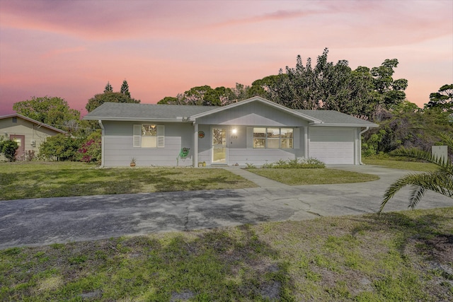 ranch-style home featuring a front lawn, an attached garage, and driveway