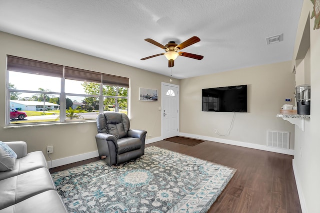 living room with visible vents, ceiling fan, baseboards, and wood finished floors