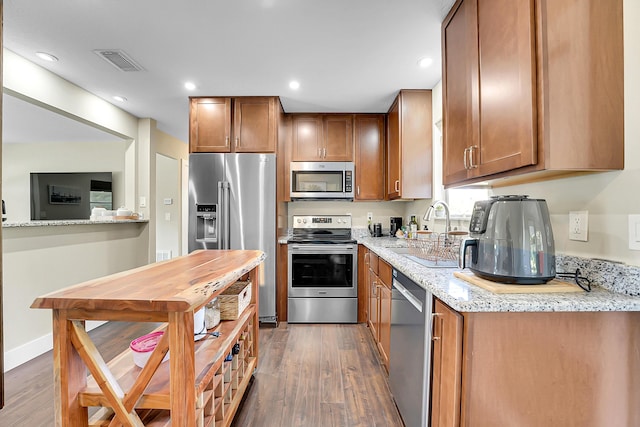 kitchen with a sink, visible vents, dark wood-type flooring, and appliances with stainless steel finishes