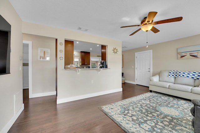 living room with dark wood-style floors, visible vents, and baseboards