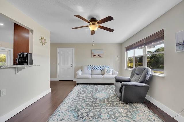 living room with a ceiling fan, dark wood-style floors, and baseboards