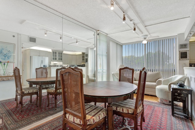 dining room with a ceiling fan, rail lighting, visible vents, and a textured ceiling