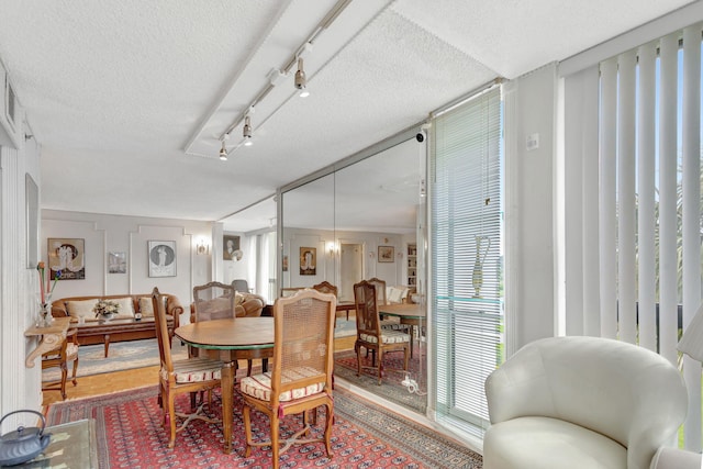 dining space featuring track lighting, a textured ceiling, and wood finished floors