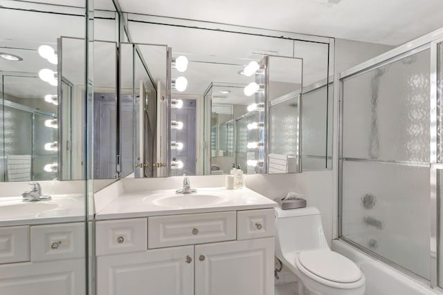 bathroom featuring toilet, shower / bath combination with glass door, and vanity