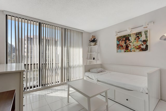 bedroom with expansive windows, a textured ceiling, and light tile patterned flooring