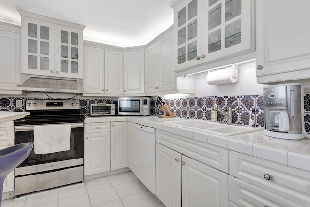 kitchen with stainless steel appliances, white cabinetry, under cabinet range hood, and decorative backsplash