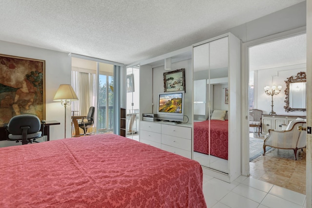 bedroom with multiple closets, light tile patterned floors, floor to ceiling windows, and a textured ceiling