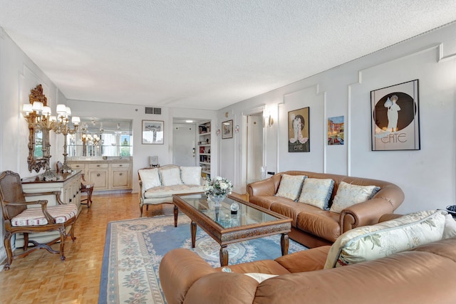 living room with a chandelier, visible vents, and a textured ceiling