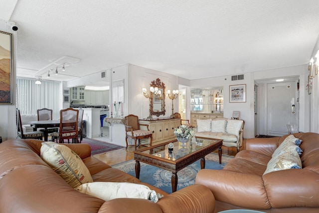 living room with a textured ceiling, visible vents, and an inviting chandelier