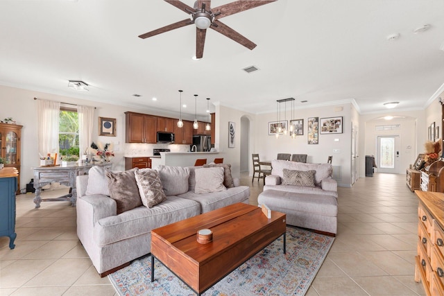 living area with arched walkways, light tile patterned floors, visible vents, and crown molding