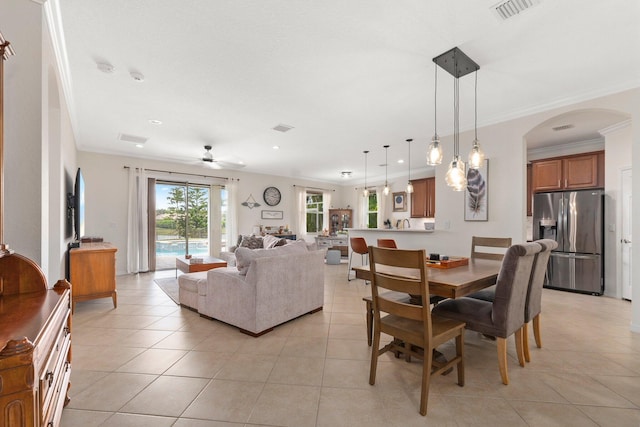 dining area featuring light tile patterned floors, arched walkways, visible vents, and crown molding