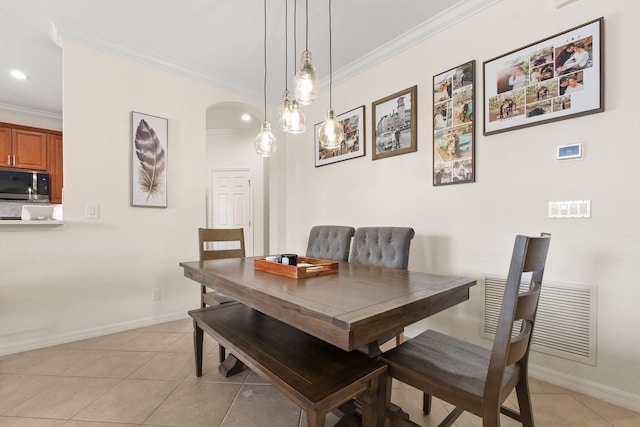 dining area with arched walkways, visible vents, ornamental molding, light tile patterned flooring, and baseboards