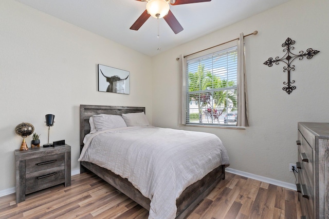 bedroom featuring wood finished floors, a ceiling fan, and baseboards