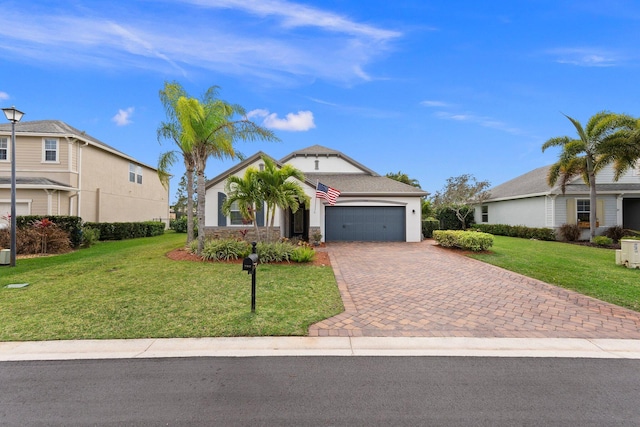 view of front of home with a garage, decorative driveway, a front yard, and stucco siding