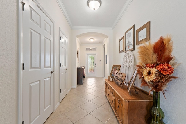 entryway featuring arched walkways, ornamental molding, light tile patterned flooring, and baseboards