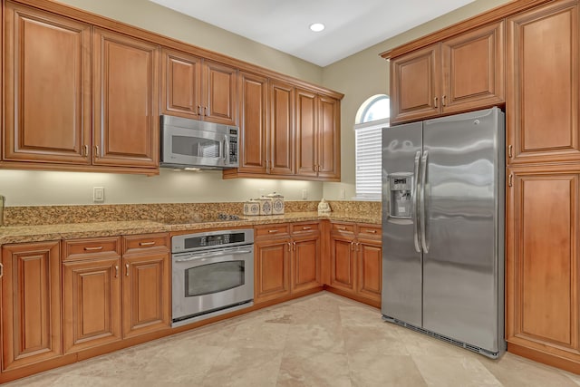 kitchen with brown cabinetry, recessed lighting, appliances with stainless steel finishes, and light stone counters