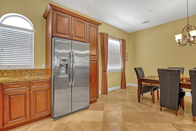 kitchen with a notable chandelier, visible vents, stainless steel fridge, and brown cabinets