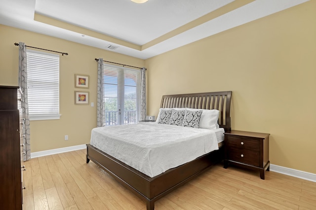 bedroom with light wood-type flooring, visible vents, baseboards, and access to outside