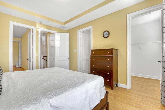 bedroom featuring a closet, baseboards, light wood-style floors, and a spacious closet