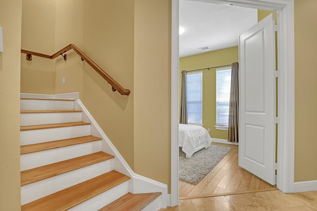 stairs with wood finished floors, baseboards, and visible vents