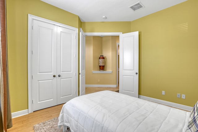bedroom with visible vents, baseboards, light wood-style floors, and a closet