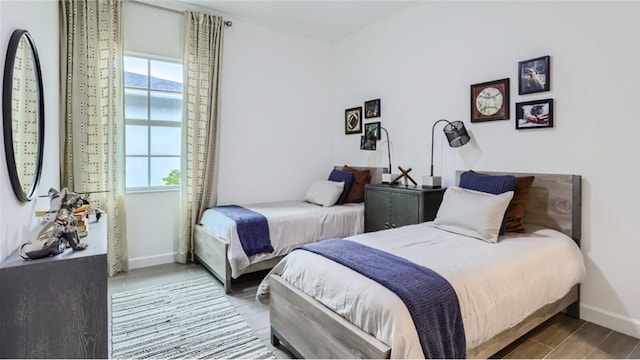 bedroom featuring multiple windows, wood finished floors, and baseboards