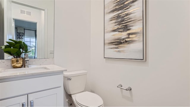 half bathroom featuring visible vents, vanity, and toilet