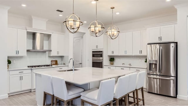 kitchen featuring appliances with stainless steel finishes, light countertops, crown molding, wall chimney range hood, and a sink