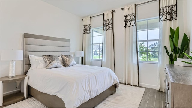 bedroom featuring wood finish floors, multiple windows, and baseboards