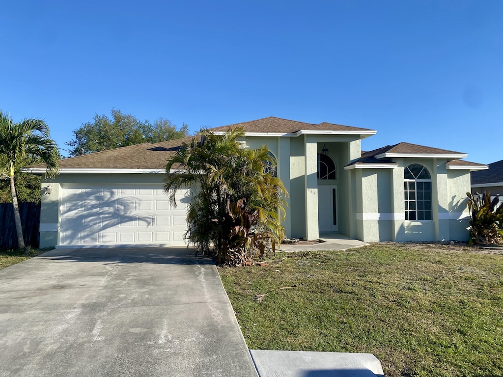 view of front of house featuring a front yard, concrete driveway, an attached garage, and stucco siding