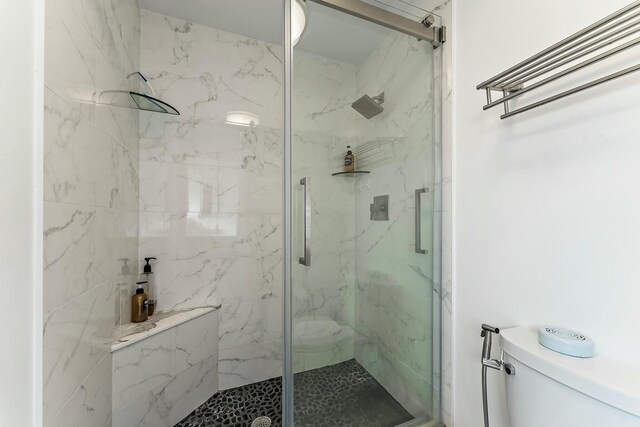 full bathroom with a marble finish shower and toilet