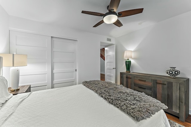 bedroom with ceiling fan, visible vents, dark wood-style flooring, and a closet