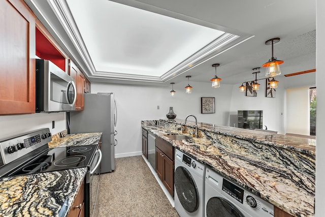 kitchen featuring a raised ceiling, appliances with stainless steel finishes, a sink, and washer / dryer