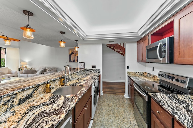 kitchen with stainless steel appliances, washer / clothes dryer, open floor plan, a sink, and baseboards