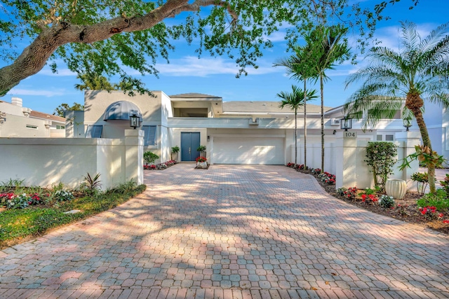 view of front of house with a fenced front yard, stucco siding, an attached garage, and decorative driveway