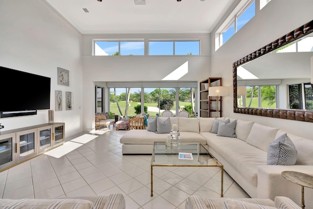 living room featuring visible vents, ornamental molding, a towering ceiling, and tile patterned flooring