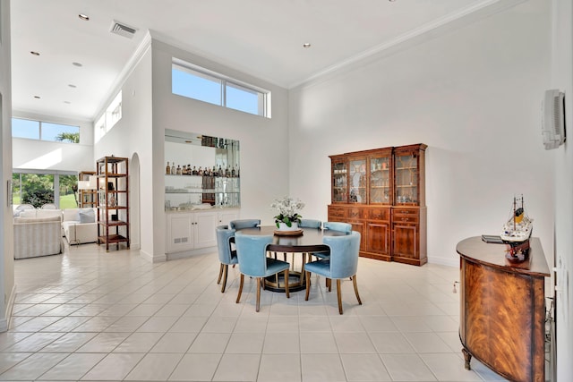 dining room featuring light tile patterned flooring, baseboards, a towering ceiling, and ornamental molding