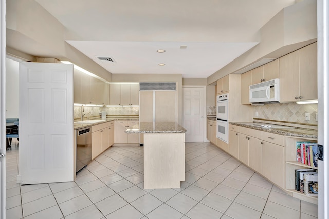 kitchen with white appliances, light tile patterned flooring, visible vents, and a kitchen island