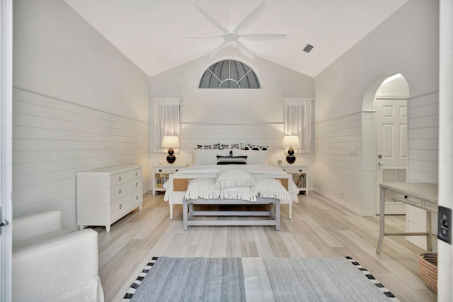 bedroom featuring light wood-style flooring, wooden walls, wainscoting, and high vaulted ceiling