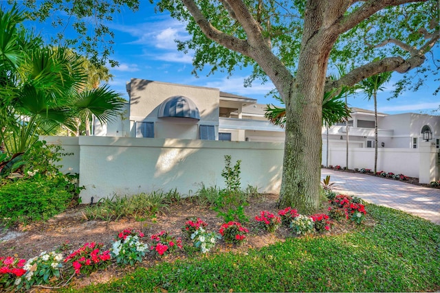 view of side of home with driveway, a fenced front yard, and stucco siding