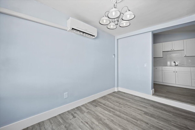 unfurnished dining area featuring baseboards, wood finished floors, an inviting chandelier, a sink, and a wall mounted AC