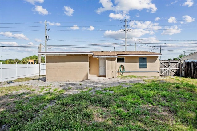 rear view of property with a fenced backyard and stucco siding