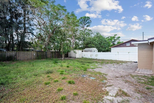 view of yard featuring a storage shed, a fenced backyard, and an outbuilding