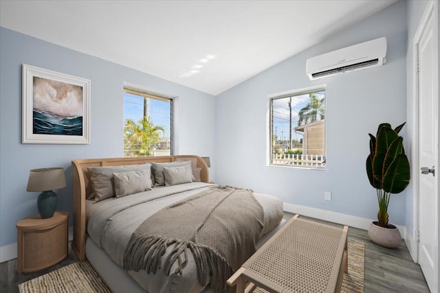 bedroom with lofted ceiling, a wall unit AC, baseboards, and wood finished floors