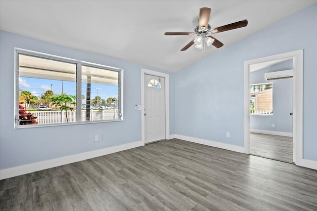 spare room with lofted ceiling, wood finished floors, a ceiling fan, baseboards, and a wall mounted air conditioner