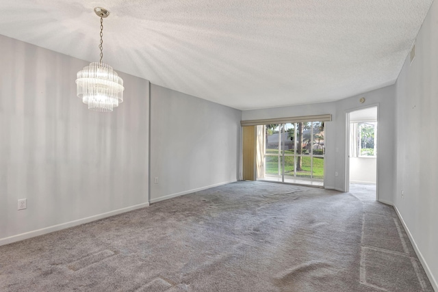 unfurnished room with baseboards, visible vents, a textured ceiling, carpet flooring, and a chandelier