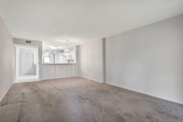 unfurnished living room with a textured ceiling, carpet, visible vents, and baseboards