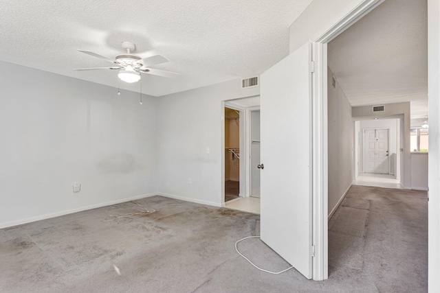 carpeted spare room featuring visible vents, ceiling fan, a textured ceiling, and baseboards