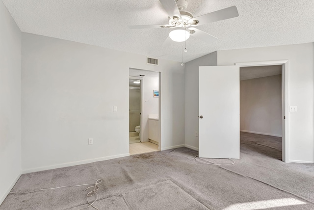 unfurnished bedroom featuring a textured ceiling, ensuite bathroom, visible vents, baseboards, and carpet