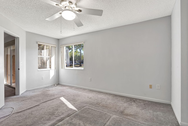 carpeted empty room with a ceiling fan, baseboards, and a textured ceiling